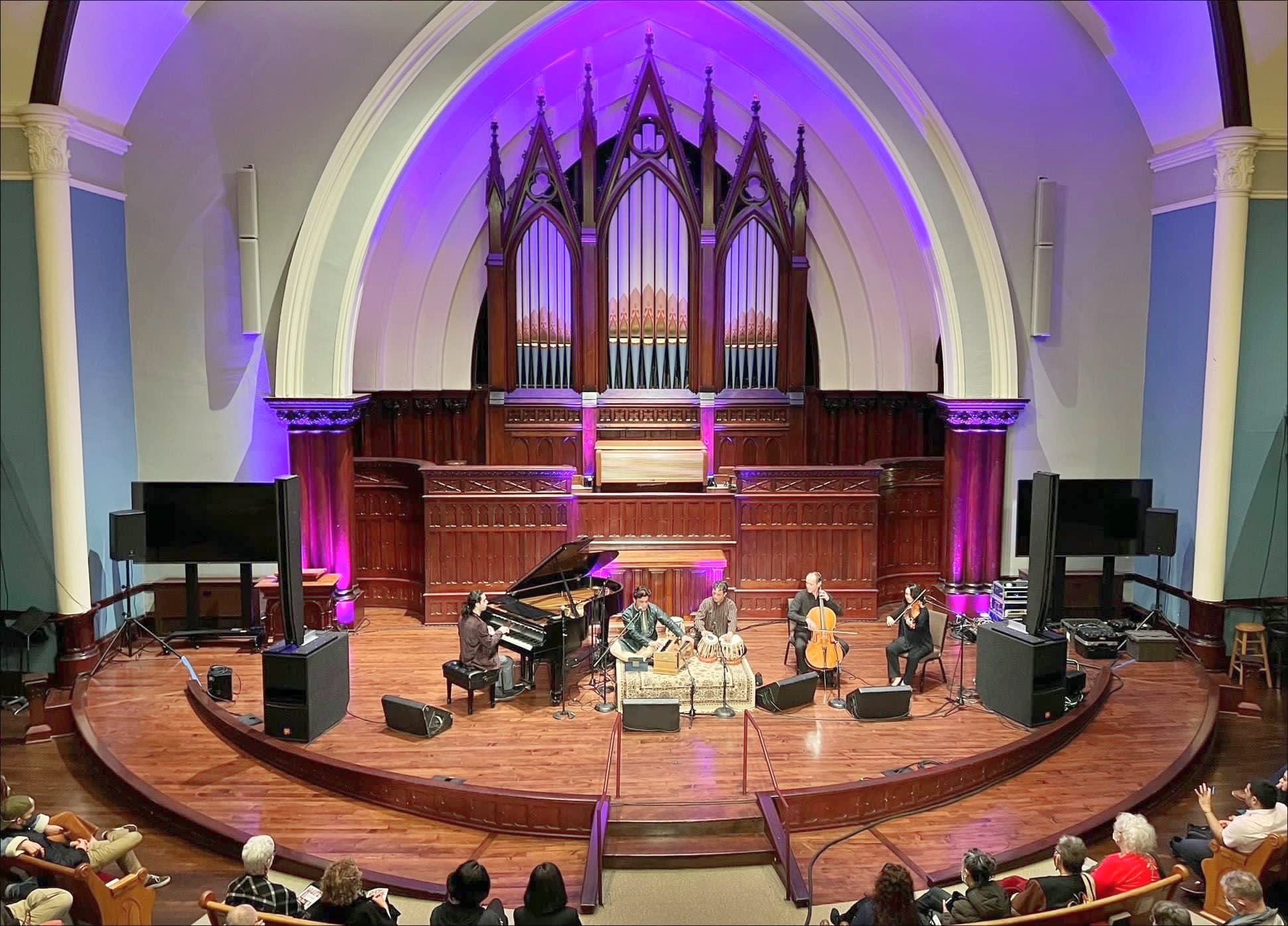 Elham Fanoos and ensemble performing in a church hall beneath a pipe organ