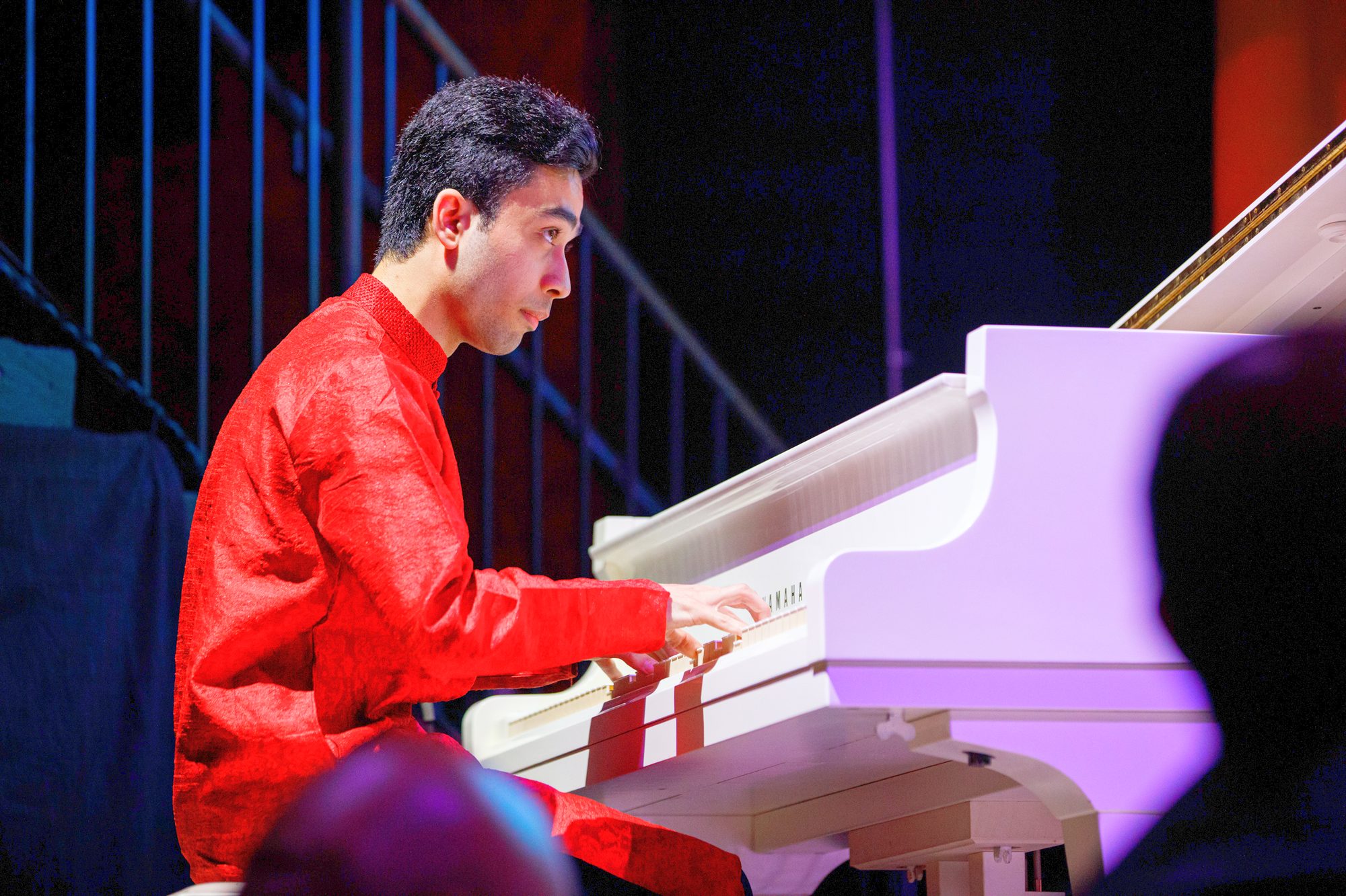 Elham Fanoos in profile, playing a white grand piano
