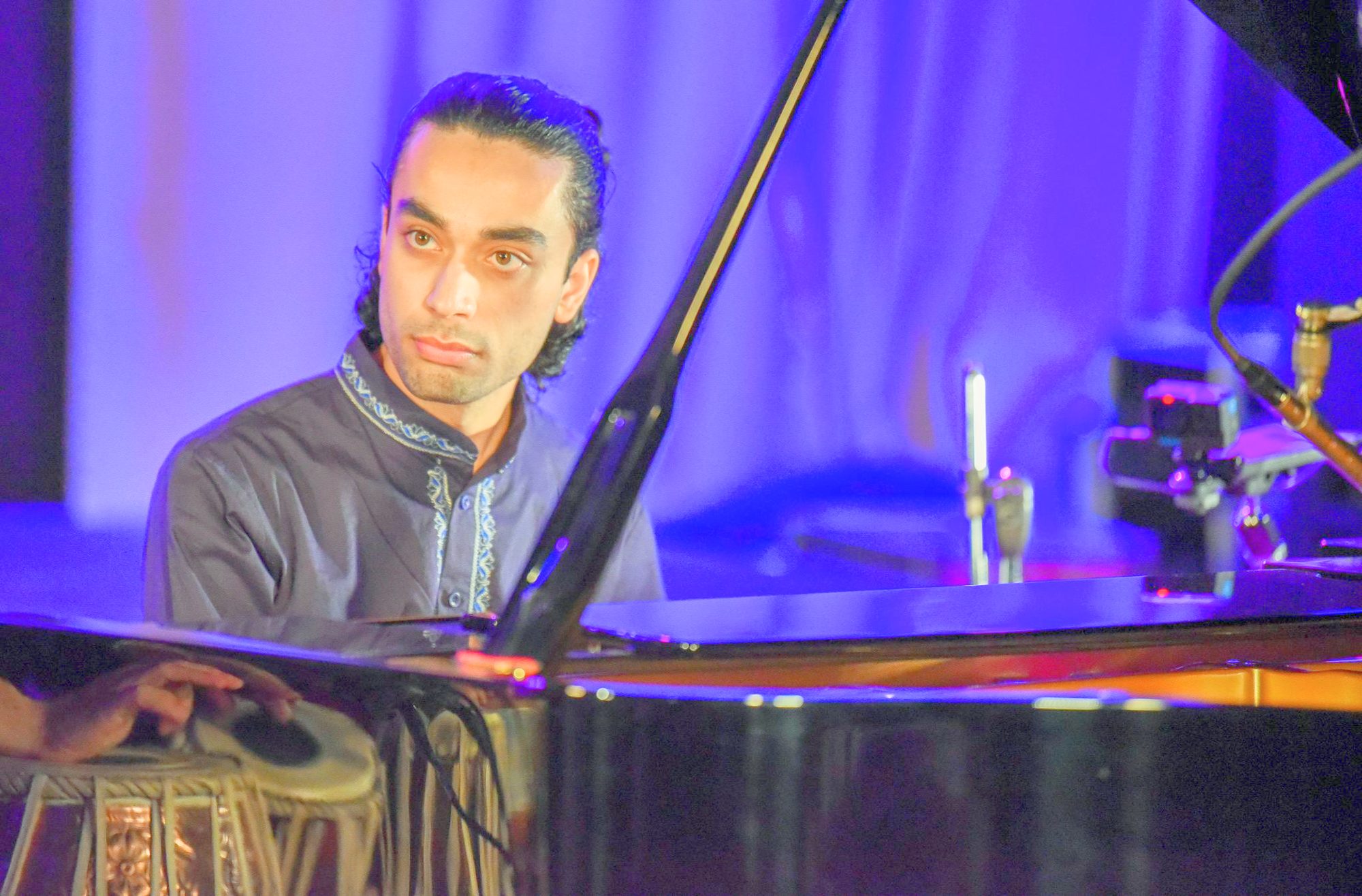 Elham Fanoos seated at the piano, looking toward the audience