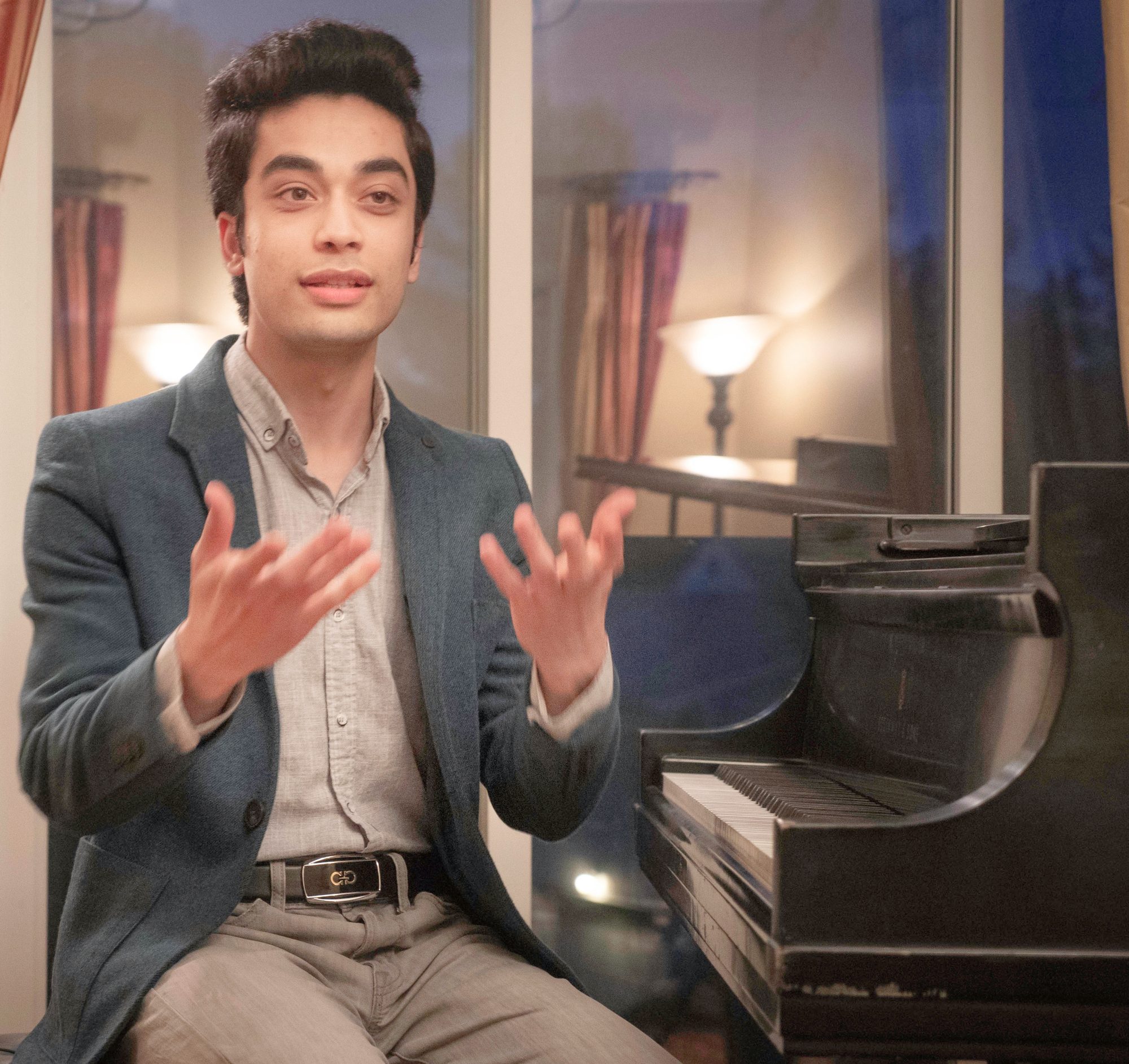 Elham Fanoos seated beside a piano, speaking