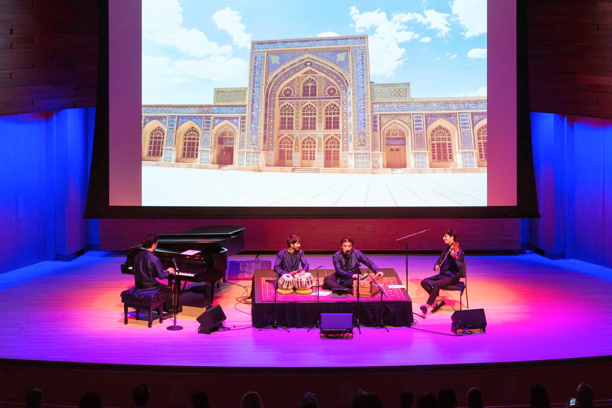 Elham Fanoos and ensemble on stage beneath a projected image of a tiled mosque façade